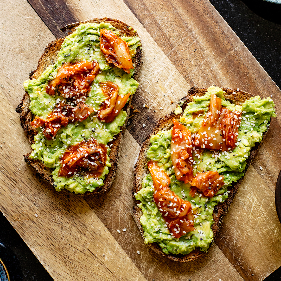 Kimchi Avocado Toast with creamy avocado, spicy bibigo kimchi, and crispy sourdough bread, a flavorful fusion of ingredients.