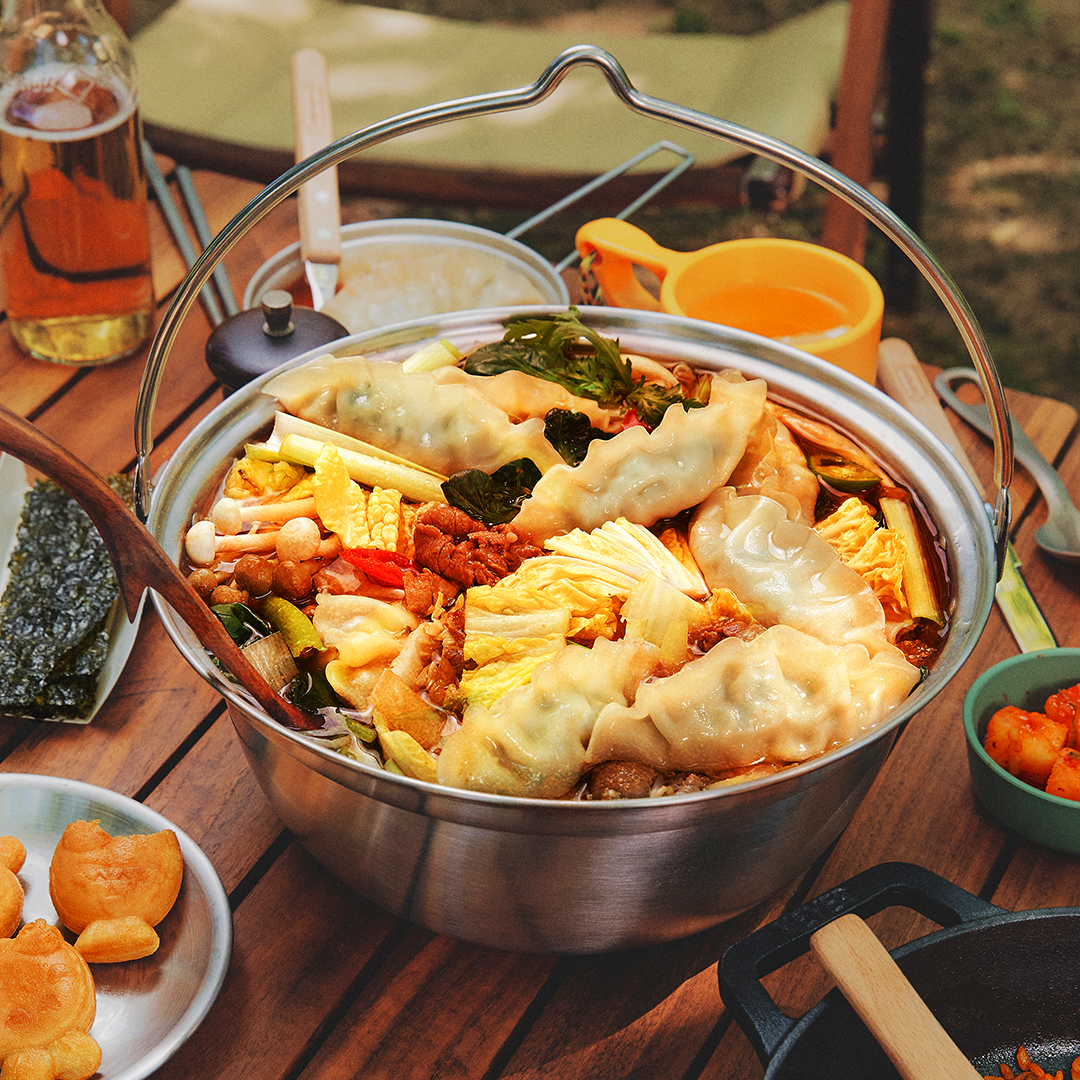 Picture of hotpot filled with savory broth, mandu dumplings, fresh vegetables, and colorful ingredients.